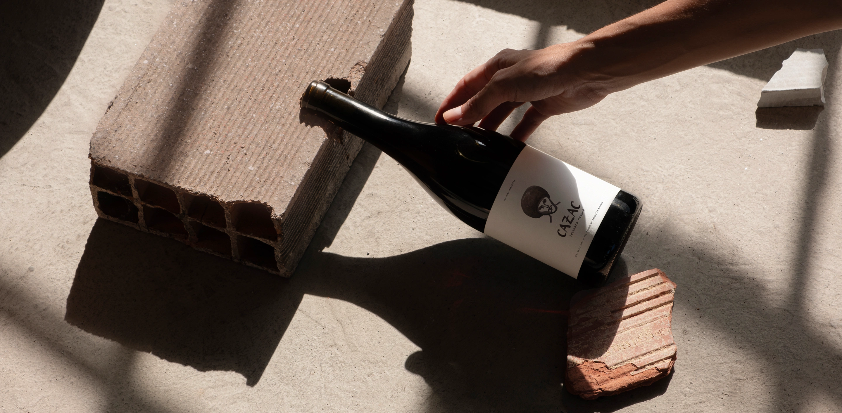 A Cazac wine bottle resting between bricks in warm sunlight