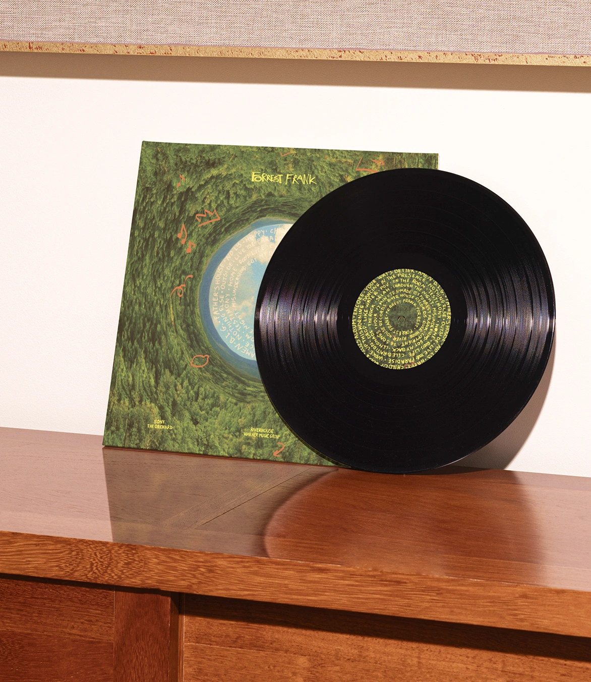 Black vinyl record beside the green album sleeve