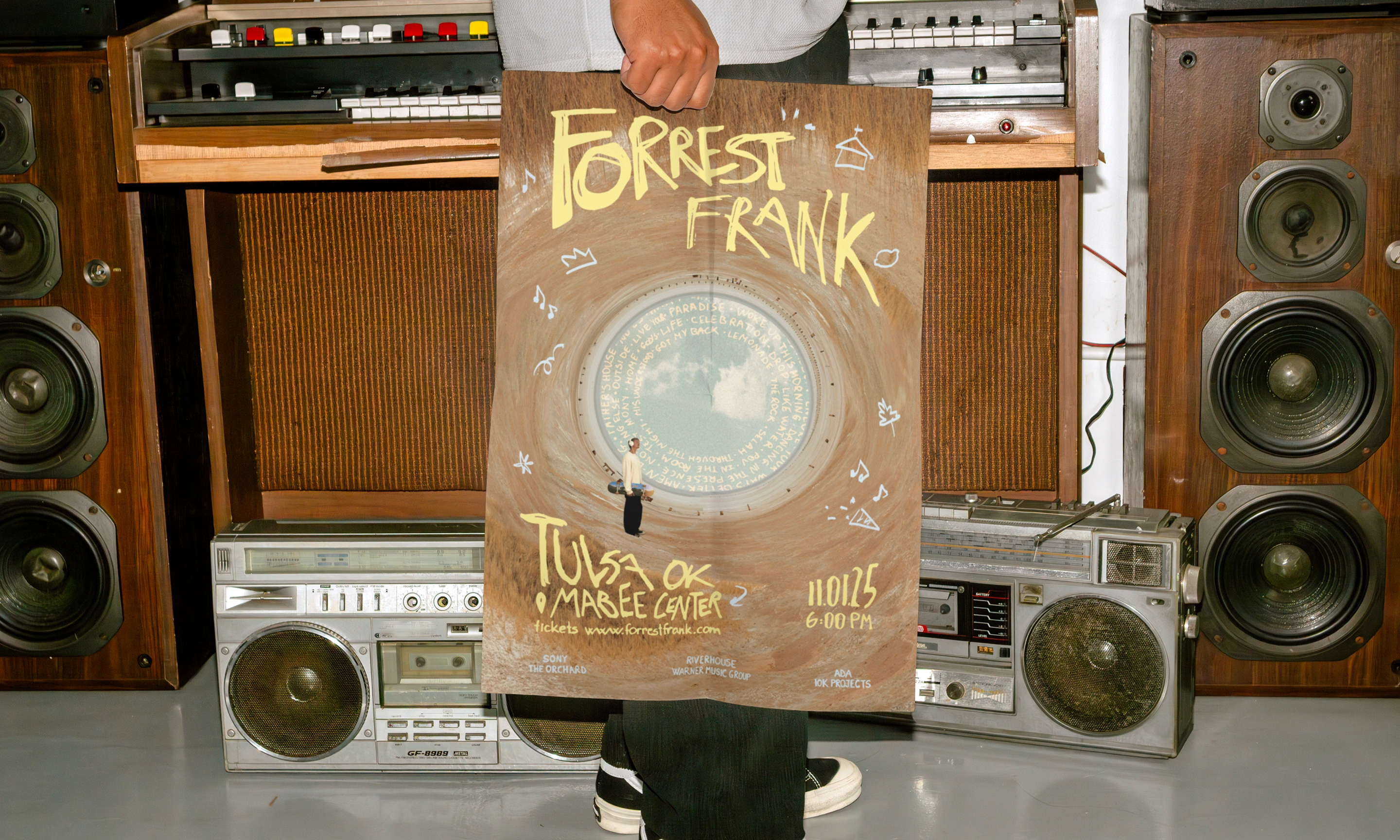 A person holding the Tulsa poster in front of vintage sound equipment
